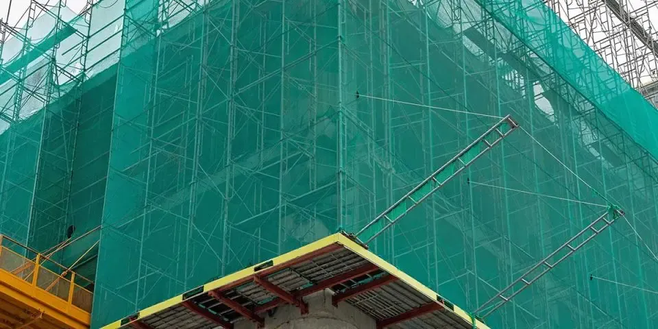 Construction site with workers wearing harnesses and safety nets below